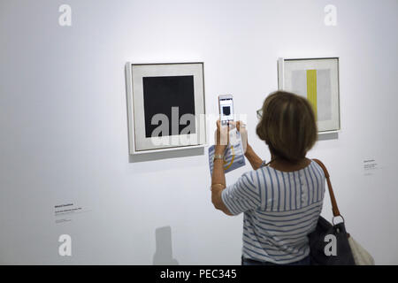 Visitor uses a smartphone to photograph the painting 'Black Square' by Russian avant-garde painter Nikolai Suetin dated from the early 1920s displayed at the exhibition in the Centre Pompidou in Paris, France. The painting is a copy after the famous painting by Russian avant-garde painter Kazimir Malevich. Painting by Nikolai Suetin entitled 'Composition with a Yellow Stripe' from the early 1920s is seen in the picture at the right. The exhibition devoted to the Russian avant-garde in Vitebsk (1918-1922) runs till 16 July 2018. Stock Photo