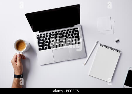 cropped shot of man folding coffee cup at workplace with supplies on white surface for mockup Stock Photo