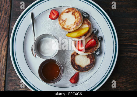 top view of delicious cheese pancakes with bowls of dippings on wooden table Stock Photo