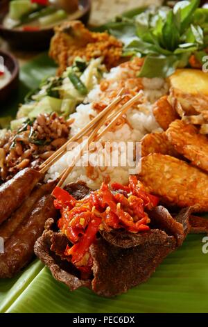Indonesian Rijsttafel on Banana Leaf. Rice with various dishes from Sumatra, Java, and Sulawesi are served on whole banana leaf. Stock Photo