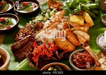 Indonesian Rijsttafel on Banana Leaf. Rice with various dishes from Sumatra, Java, and Sulawesi are served on whole banana leaf. Stock Photo