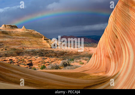 A rainbow crests the Wave, a multi-colored chute that has been cut into a sandstone mountain in the Coyote Buttes area of the Paria Canyon-Vermillion  Stock Photo