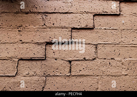 Old faded cracked brick wall in angled light Stock Photo