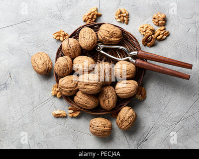 Whole walnuts and kernels on gray background and nutcracker. Stock Photo