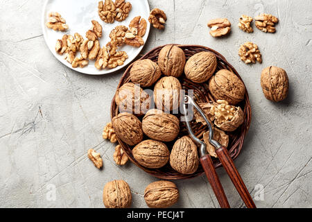 Whole walnuts and kernels on gray background and nutcracker. Stock Photo