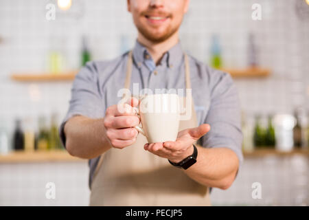 Wonderful taste. Selective focus of a tea cup being held by a nice handsome pleasant man while working in the cafe Stock Photo