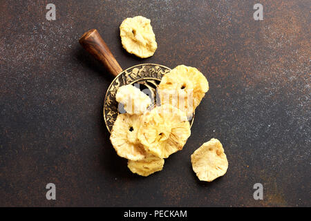 Dried candied pineapple rings. Sliced sweet fruits on brown concrete background. Top view. Stock Photo
