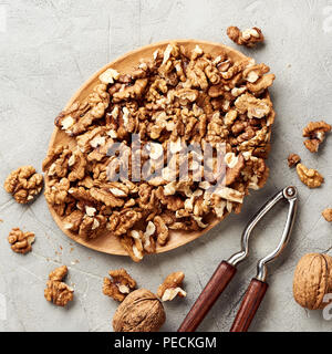 Walnut kernels on gray background and nutcracker. Stock Photo