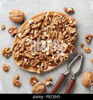 Walnut kernels on gray background and nutcracker. Stock Photo