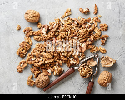 Walnut kernels on gray background and nutcracker. Stock Photo