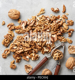 Walnut kernels on gray background and nutcracker. Stock Photo