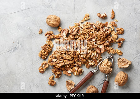 Walnut kernels on gray background and nutcracker. Stock Photo