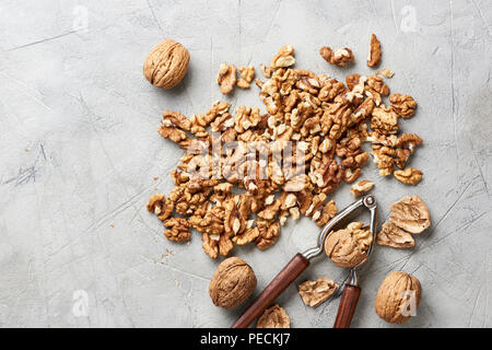 Walnut kernels on gray background with nutcracker. Stock Photo