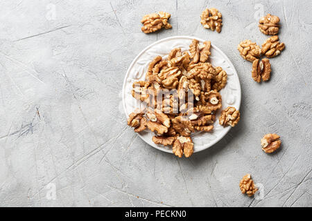 Walnut kernels on white plate over gray background. Stock Photo