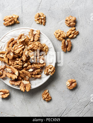 Walnut kernels on white plate over gray background. Stock Photo