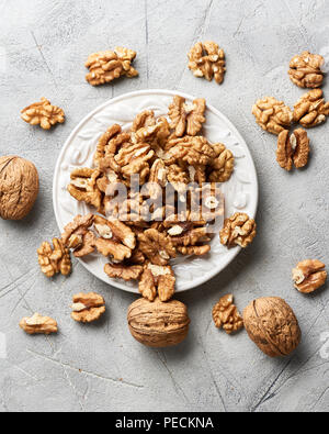 Walnut kernels on white plate over gray background. Stock Photo