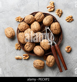 Whole walnuts and kernels on gray background and nutcracker. Stock Photo