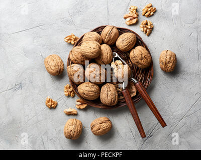 Whole walnuts and kernels on gray background and nutcracker. Stock Photo