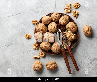 Whole walnuts and kernels on gray background and nutcracker. Stock Photo