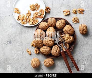 Whole walnuts and kernels on gray background and nutcracker. Stock Photo