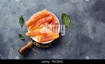 Dried sweet papaya sticks. Candied fruits on gray background. Top view. Stock Photo