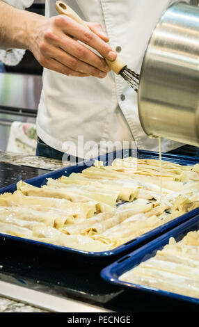 Cooking lasagna. The cook pours sauce. Italian Cuisine. Stock Photo