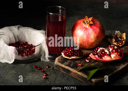 Pomegranate fruits with grains and leaves on the table. Make juice. Dark moody. Stock Photo