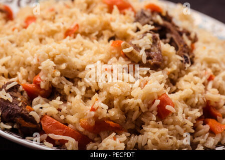 Pilaf on plate with oriental ornament. Central-Asian cuisine - Plov. Macro. Stock Photo