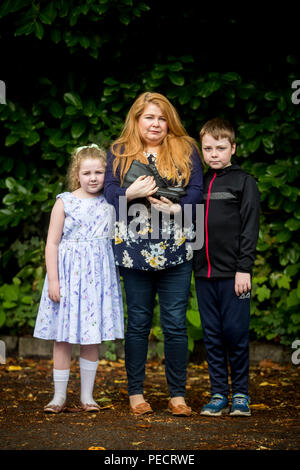 Cat Wilkinson, daughter of Michael Gallagher, with her daughter Fara, aged 8 and son Fynn, aged 10, outside the offices of Omagh Support &amp; Self Help Group, holding her brother Aiden's work boots, which he bought on the day of the Omagh bomb. Aiden Gallagher, who was killed in the bomb, had been preparing to emigrate to the United States, his sister has revealed. Stock Photo