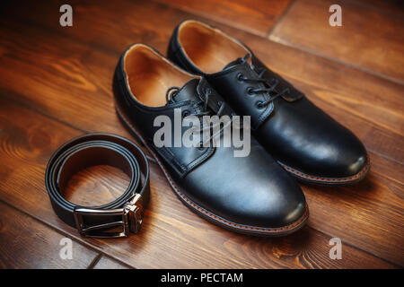 Black leather male shoes and belt on wooden background, closeup Stock Photo