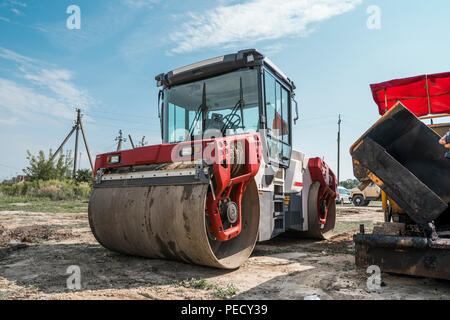 Red Heavy Vibration roller at asphalt pavement works. Road repairing. Road construction and repairing asphalt pavement works with a blue sky Stock Photo