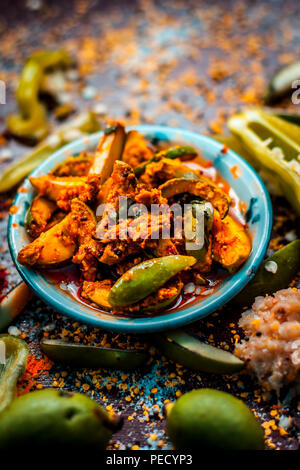 Close up of Aam ka achar or kari ka achar or traditional raw mango pickle with all its ingredients and speiceis on a wooden surface in drak Gothic col Stock Photo