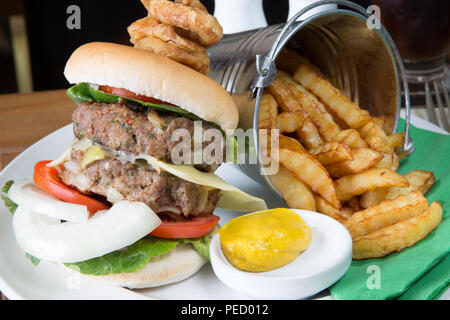 Homemade double hamburger and cheese with a bucket/pail of potato chips/fries and English mustard Stock Photo