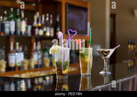 Three cocktails on the bar - Mojito with ice and straw, Pina Colada with a chocolate heart Stock Photo