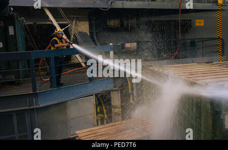 A Boatswain's Mate 3rd Class washes down a truck in the well deck of the San Antonio-class amphibious transport dock USS Anchorage (LPD 23) in the Gulf of Aden on Aug. 3, 2015. Anchorage, part of the Essex Amphibious Ready Group with the embarked 15th Marine Expeditionary Unit, supports maritime security operations and theater security cooperation within the U.S. 5th Fleet area of operations. Routine maintenance ensures operational readiness of vehicles and well deck equipment. Stock Photo