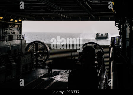 Landing Craft Air Cushion (LCAC) 65 approaches the well deck of USS Anchorage (LPD 23) on Aug. 3, 2015, during operations in the Gulf of Aden. The San Antonio-class amphibious transport dock, part of the Essex Amphibious Ready Group with the embarked 15th Marine Expeditionary Unit, supports maritime security operations and theater security cooperation within the U.S. 5th Fleet area. LCACs transport vehicles, troops, and equipment from ship to shore in amphibious operations. Stock Photo