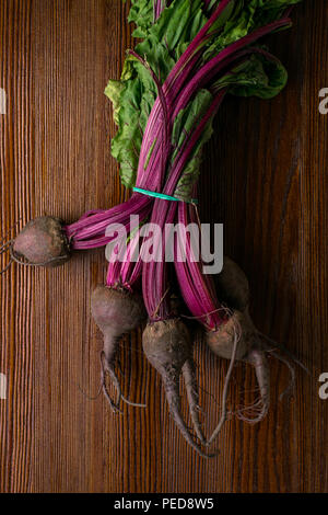 Red organic bunch Beetroot with herbage green leaves with foliage, on wooden background Stock Photo