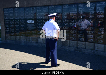 Chief Petty Officer Christopher Sheppard, officer in charge, Aids to Navigation Team Astoria, Ore., looks at a memorial wall at the Maritime Memorial Park in Astoria after the annual Seaman's Memorial ceremony, Aug. 7, 2015. Sheppard has a family name on the wall, which he was searching for while paying tribute to the other names. (U.S. Coast Guard photo by Petty Officer 1st Class Levi Read) Stock Photo