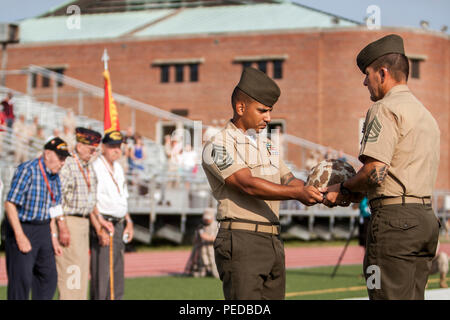 U.S. Marines pass an M1 steel helmet received from veterans of 4th Marine Division (4th MARDIV) during the 4th MARDIV Association Deactivation Ceremony at Liversedge Field, Camp Lejeune, N.C., Aug. 6, 2015. Veterans of 4th MARDIV and their families visited the Camp Lejeune area for a final muster, which included visits to the Lejeune Memorial Gardens, new equipment demonstrations, tours in the local community and concluded with the deactivation ceremony for the unit. (U.S. Marine Corps photo by Cpl. Allison DeVries, MCIEAST-MCB CAMLEJ Combat Camera/Released) Stock Photo