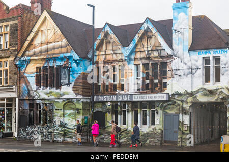 Visitors walking past the Steam Crane ale house and kitchen with street art on North Street, Bristol on a wet rainy day in August Stock Photo