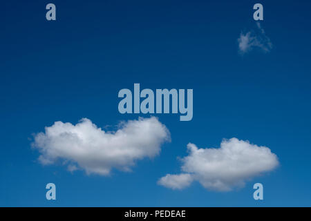 Two clouds floating across a deep blue sky. Stock Photo