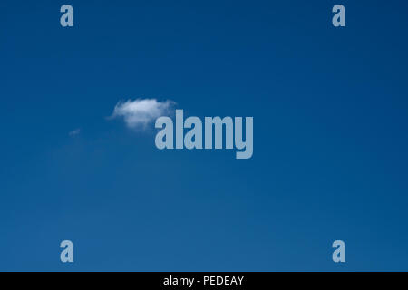 small cloud in a large cloudless expanse of deep blue sky. Stock Photo