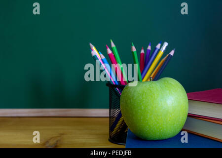 green apple resting on the book with chalk board as background Stock Photo