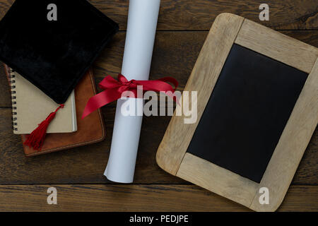 Table top view aerial image of Graduation of education season background concept.Flat lay accessories cap with certificate paper & book on modern rust Stock Photo