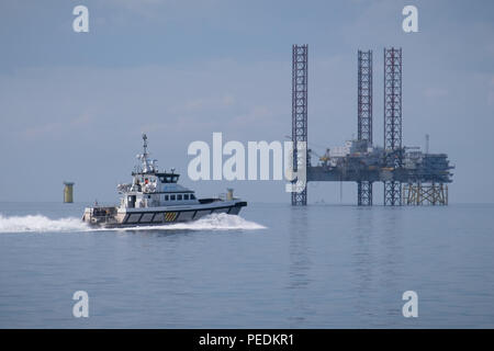 Seacat Volunteer heading to Atlantic Amsterdam, seen in the distance jacked up adjacent to Offshore Substation (OSS) Z01 on Race Bank Offshore Wind Farm, UK Stock Photo