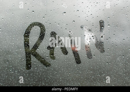 Close up of raindrops and the word rain written in condensation on a window (windscreen, windshield) Stock Photo