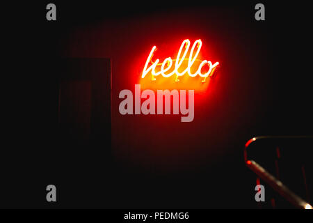 A neon sign saying hello on a red wall in a dark corridor at night Stock Photo