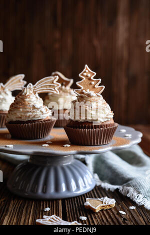 Homemade gingerbread cupcakes decorated with cinnamon and Christmas cookies and snowflake sprinkles Stock Photo