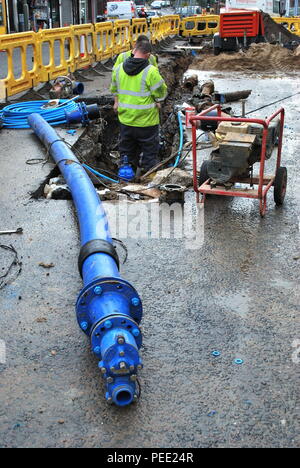 Construction worker repairing water pipe on the street in London Stock Photo