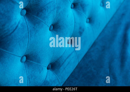 Velour surface of sofa close-up. Coach-type velours screed tightened with buttons. Blue chesterfield style quilted upholstery backdrop close up Stock Photo